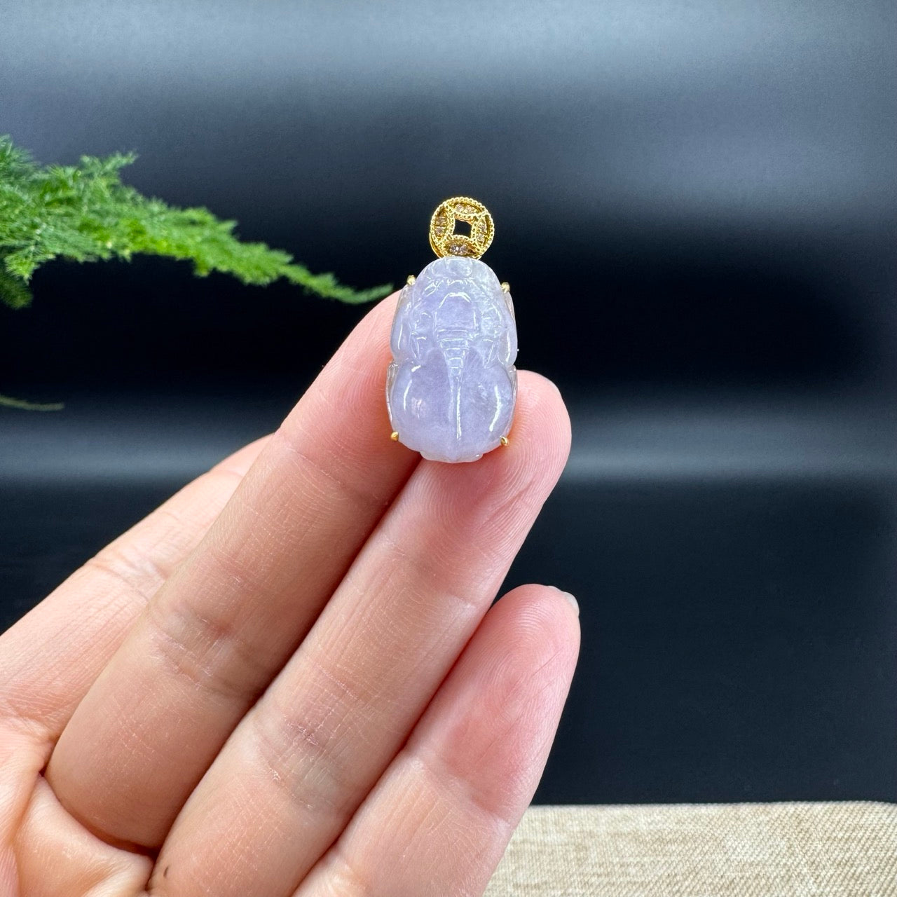 The shape of the pendant is that of a pixiu. The jade is icy lavender color, and it is surrounded by 18k yellow gold with diamonds.